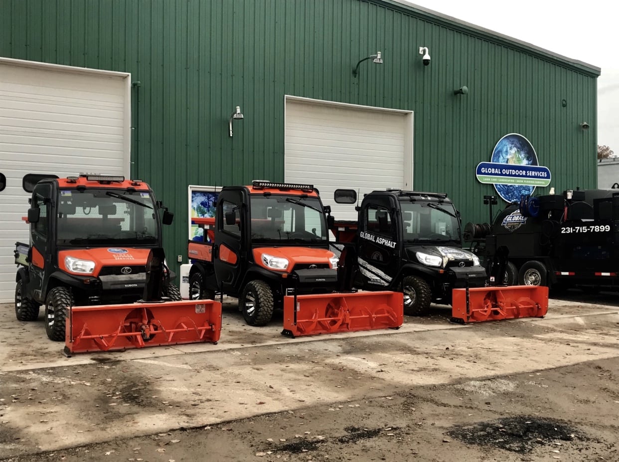 Three sidewalk snow blowers lined up outside the Global Asphalt shop